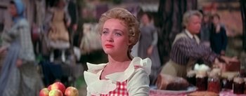 Movie still from “Seven Brides for Seven Brothers” (1954), directed by Stanley Donen – A woman in a checkered dress is looking to her left; Medium shot, Over the shoulder angle