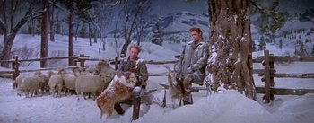 Movie still from “Seven Brides for Seven Brothers” (1954), directed by Stanley Donen – A couple of men sitting on top of a wooden bench; Wide shot, High angle