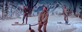 Movie still from “Seven Brides for Seven Brothers” (1954), directed by Stanley Donen – A man in a brown jacket is using an axe; Medium shot, Low angle