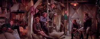 Movie still from “Seven Brides for Seven Brothers” (1954), directed by Stanley Donen – A group of people sitting on a ladder in a room; Wide shot, High angle