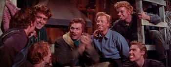 Movie still from “Seven Brides for Seven Brothers” (1954), directed by Stanley Donen – Two men sitting next to each other in a room; Medium shot, Low angle