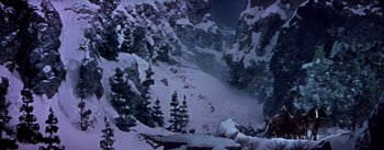 Movie still from “Seven Brides for Seven Brothers” (1954), directed by Stanley Donen – A view from above of a snowy landscape with trees; Extreme Wide shot, High angle