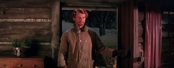 Movie still from “Seven Brides for Seven Brothers” (1954), directed by Stanley Donen – A man in a brown coat standing in front of a window in the snow; Medium shot, Low angle