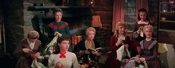 Movie still from “Seven Brides for Seven Brothers” (1954), directed by Stanley Donen – A group of women sitting in front of a fireplace; Medium shot, High angle