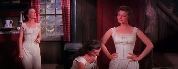 Movie still from “Seven Brides for Seven Brothers” (1954), directed by Stanley Donen – A woman in a white dress standing next to another woman in a white dress; Medium shot, Low angle