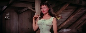 Movie still from “Seven Brides for Seven Brothers” (1954), directed by Stanley Donen – A beautiful woman in a white corset holding a cat; Medium shot, Low angle