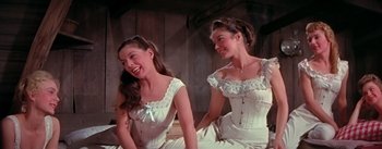 Movie still from “Seven Brides for Seven Brothers” (1954), directed by Stanley Donen – Two women in white dresses sitting next to each other; Medium shot, Low angle