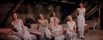 Movie still from “Seven Brides for Seven Brothers” (1954), directed by Stanley Donen – A group of women sitting on top of a bed; Wide shot, Low angle