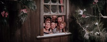 Movie still from “Seven Brides for Seven Brothers” (1954), directed by Stanley Donen – A group of people standing next to each other in front of a window; Medium shot, Low angle
