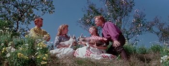 Movie still from “Seven Brides for Seven Brothers” (1954), directed by Stanley Donen – A group of people sitting on the ground with animals; Medium shot, Low angle