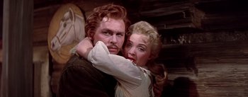 Movie still from “Seven Brides for Seven Brothers” (1954), directed by Stanley Donen – A man and a woman embracing each other in front of a wooden wall; Close Up shot, Low angle