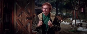Movie still from “Seven Brides for Seven Brothers” (1954), directed by Stanley Donen – A man with a red hair and a green shirt is holding his jacket; Medium shot, Low angle