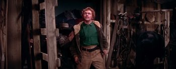 Movie still from “Seven Brides for Seven Brothers” (1954), directed by Stanley Donen – A man standing next to another man wearing a hat; Medium shot, Low angle