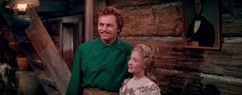 Movie still from “Seven Brides for Seven Brothers” (1954), directed by Stanley Donen – A man standing next to a woman in a green shirt; Medium shot, Low angle