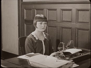 Movie still from “Seven Chances” (1925), directed by Buster Keaton – A woman sitting at a desk with a typewriter; Medium shot, High angle