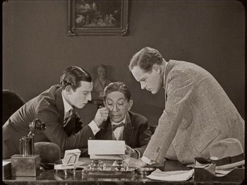 Movie still from “Seven Chances” (1925), directed by Buster Keaton – A group of men sitting at a table looking at papers; Medium shot, High angle