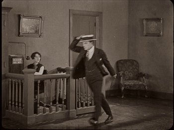 Movie still from “Seven Chances” (1925), directed by Buster Keaton – An old photo of a man in a suit and a hat; Wide shot, High angle