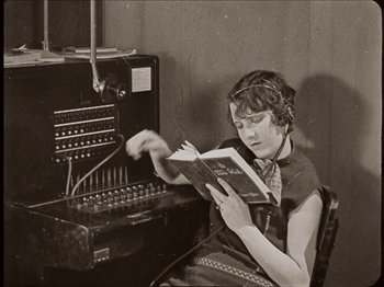 Movie still from “Seven Chances” (1925), directed by Buster Keaton – A woman sitting in front of an old fashioned computer; Medium shot, High angle