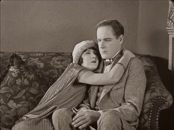 Movie still from “Seven Chances” (1925), directed by Buster Keaton – An old photo of a man and a woman sitting on a couch; Medium shot, Low angle