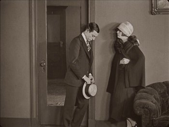 Movie still from “Seven Chances” (1925), directed by Buster Keaton – A man and a woman standing next to each other in front of a door; Wide shot, High angle