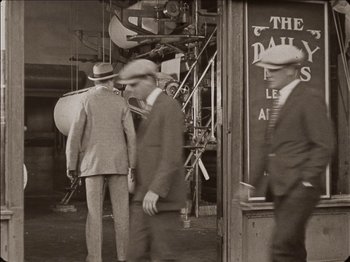 Movie still from “Seven Chances” (1925), directed by Buster Keaton – A group of men standing next to each other on the street; Wide shot, Low angle