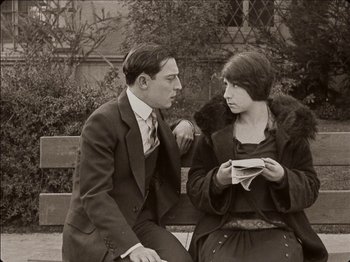 Movie still from “Seven Chances” (1925), directed by Buster Keaton – A man and a woman sitting on top of a wooden bench; Medium shot, High angle