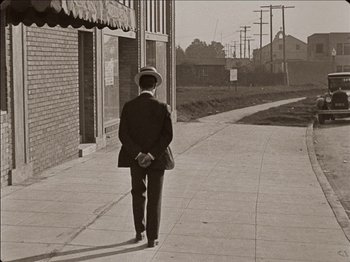 Movie still from “Seven Chances” (1925), directed by Buster Keaton – An old photo of a man walking down the street; Wide shot, High angle
