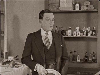 Movie still from “Seven Chances” (1925), directed by Buster Keaton – An old photo of a man in a suit holding a plate; Medium shot, High angle