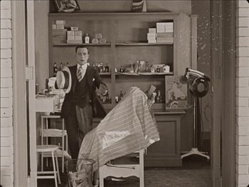 Movie still from “Seven Chances” (1925), directed by Buster Keaton – An old photo of a man in a barber shop; Wide shot, High angle