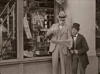 Movie still from “Seven Chances” (1925), directed by Buster Keaton – Two men standing in front of a store window; Medium shot, Low angle