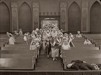Movie still from “Seven Chances” (1925), directed by Buster Keaton – An old photo of a group of people walking in a church; Extreme Wide shot, High angle
