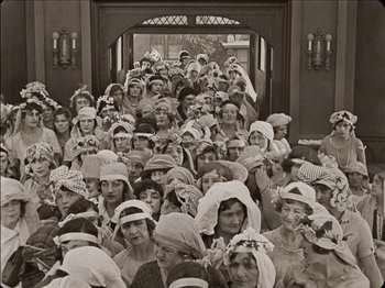 Movie still from “Seven Chances” (1925), directed by Buster Keaton – A group of people wearing hats and holding hands; Wide shot, High angle