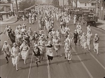 Movie still from “Seven Chances” (1925), directed by Buster Keaton – A large group of women running down a street; Extreme Wide shot, High angle