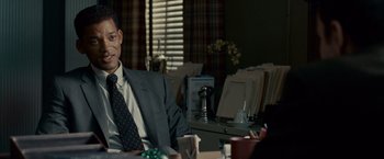 Movie still from “Seven Pounds” (2008), directed by Gabriele Muccino – A man sitting at a table in a suit and tie; Close Up shot, Over the shoulder angle