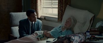 Movie still from “Seven Pounds” (2008), directed by Gabriele Muccino – An older woman in a hospital bed with a younger man; Medium shot, Over the shoulder angle