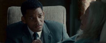 Movie still from “Seven Pounds” (2008), directed by Gabriele Muccino – A man wearing a suit and tie sitting in a chair; Close Up shot, Over the shoulder angle