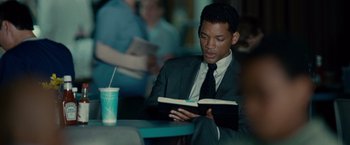 Movie still from “Seven Pounds” (2008), directed by Gabriele Muccino – A man sitting at a table reading a book; Close Up shot, Over the shoulder angle