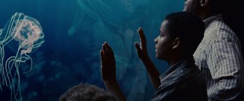 Movie still from “Seven Pounds” (2008), directed by Gabriele Muccino – A young boy looking at a fish in a body of water; Close Up shot, Low angle