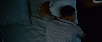 Movie still from “Seven Pounds” (2008), directed by Gabriele Muccino – A person sleeping in a bed with a pillow; Medium shot, Overhead angle