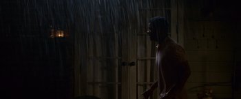 Movie still from “Seven Pounds” (2008), directed by Gabriele Muccino – A man standing in the rain in front of an open door; Wide shot, Low angle