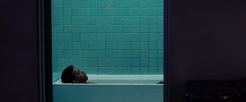 Movie still from “Seven Pounds” (2008), directed by Gabriele Muccino – A man laying in a bath tub next to a tiled wall; Medium shot, Overhead angle