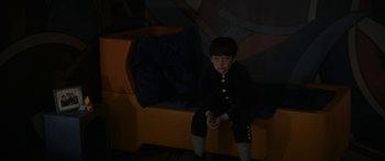 Movie still from “1899” (2022), created by Jantje Friese – A young boy sitting on a couch in a dark room; Medium shot, High angle