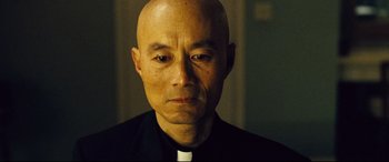 A man in a priest's outfit is looking at the camera