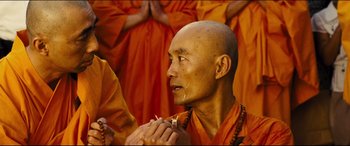 A man in orange is praying in front of a group of people