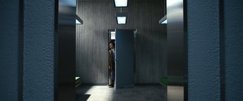 Movie still from “Severance” (2022), created by Dan Erickson – A man in a suit standing in front of an open door; Wide shot, Low angle