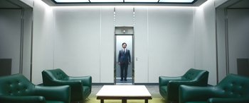 Movie still from “Severance” (2022), created by Dan Erickson – A man in a suit standing in front of an elevator; Wide shot, Low angle