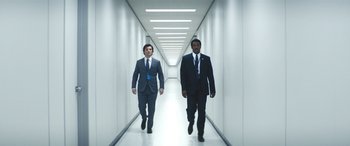 Movie still from “Severance” (2022), created by Dan Erickson – Two businessmen walking down a hallway in suits; Wide shot, Low angle