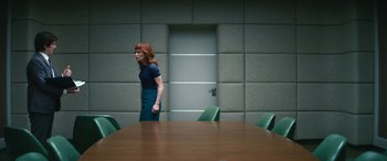 Movie still from “Severance” (2022), created by Dan Erickson – A woman standing in front of a table in a conference room; Wide shot, Over the shoulder angle