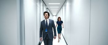 Movie still from “Severance” (2022), created by Dan Erickson – A man and a woman walking down a long hallway; Wide shot, Over the shoulder angle