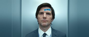 Movie still from “Severance” (2022), created by Dan Erickson – A man wearing a suit and tie with a bandage on his forehead; Close Up shot, Low angle